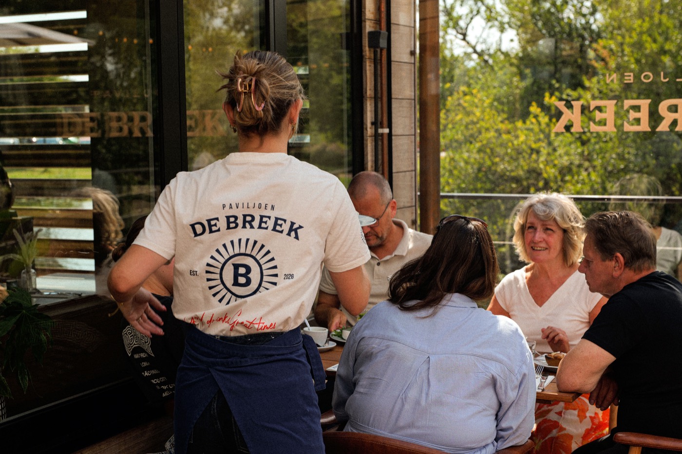 Tafels bij het raam in Paviljoen De Breek met daglicht over het water
